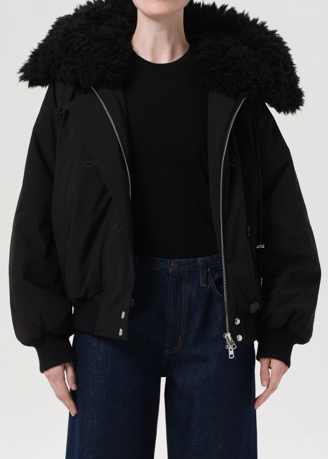 Person wearing a black jacket with a fur-lined hood on a white background