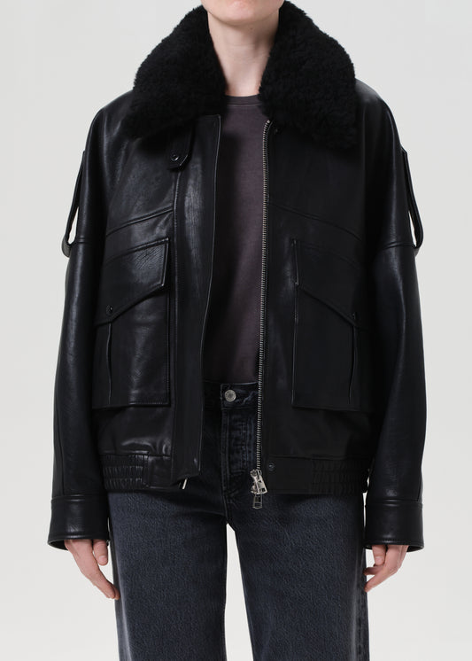 Black leather jacket with fur collar worn by a person on a white background