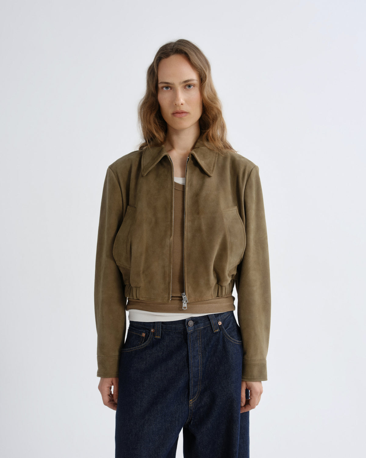 Woman wearing a brown jacket and blue jeans on a white background