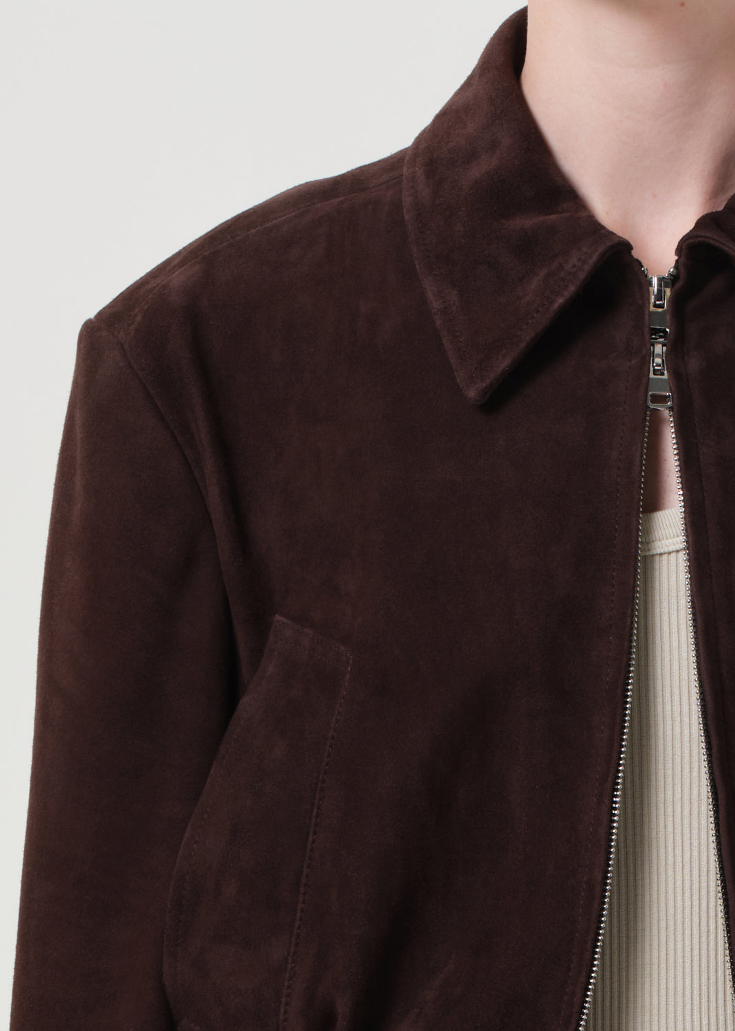 Brown suede jacket with a zipper on a plain background