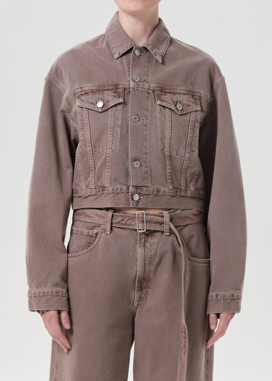 Person wearing a brown denim jacket and pants on a white background