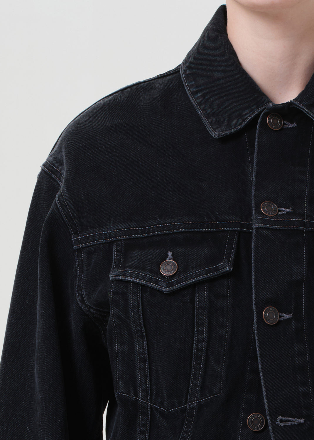 Black denim jacket with button details on a plain background