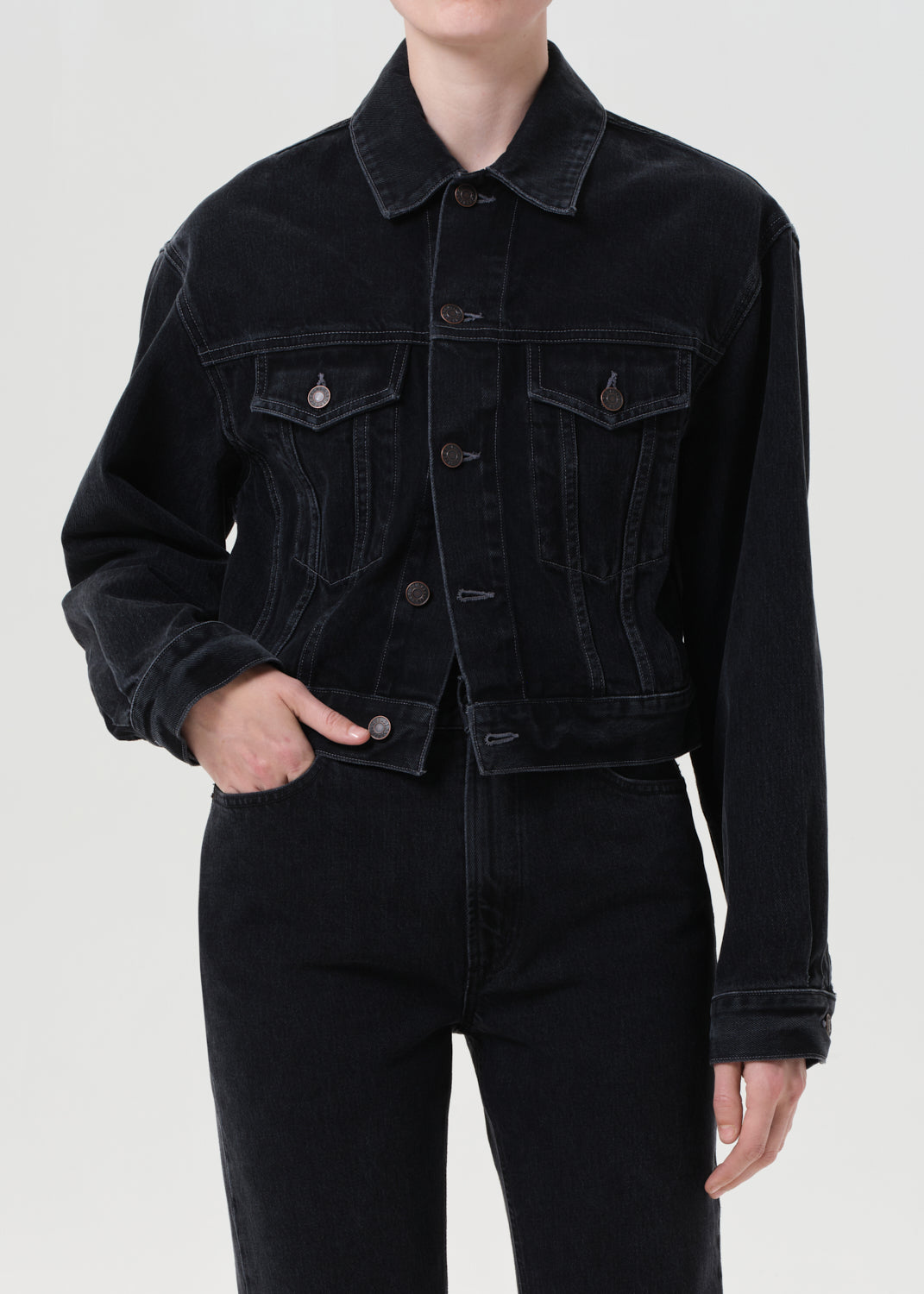 Person wearing a black denim jacket on a white background