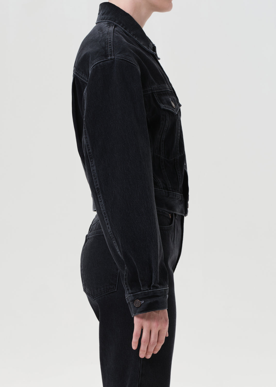 Person wearing a black denim jacket on a white background