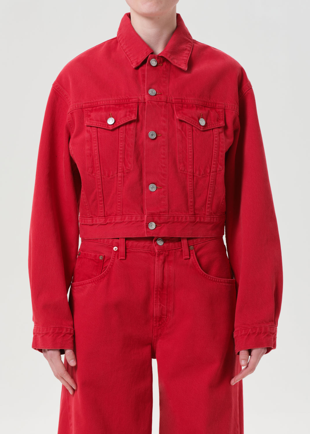 Person wearing a red denim jacket and jumpsuit on a white background