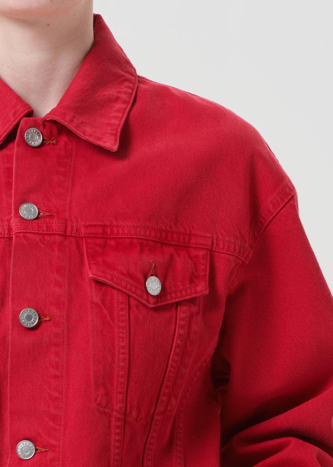 Close-up of a red denim jacket with silver buttons on a plain background