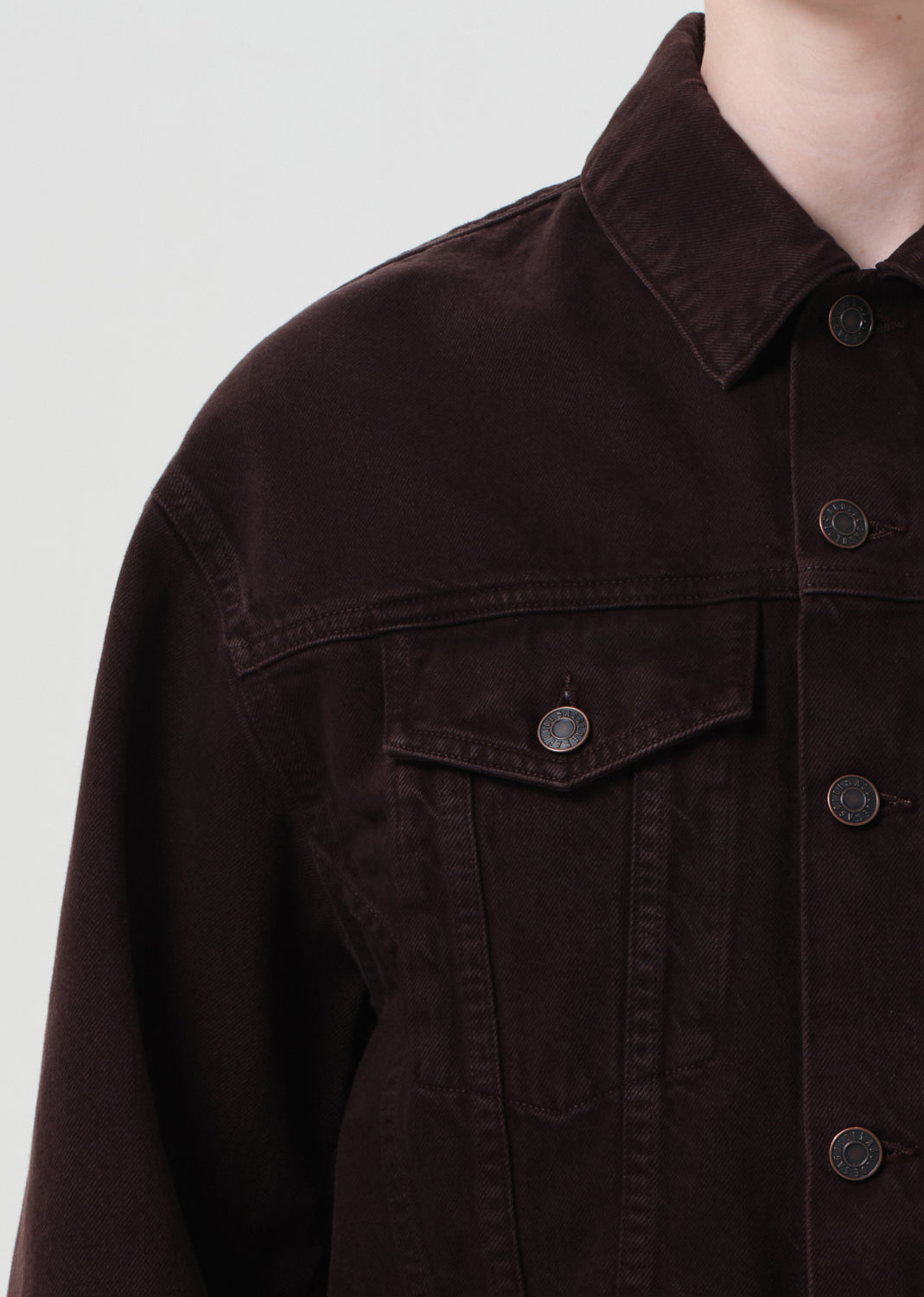 Close-up of a dark brown jacket with button details on a light gray background