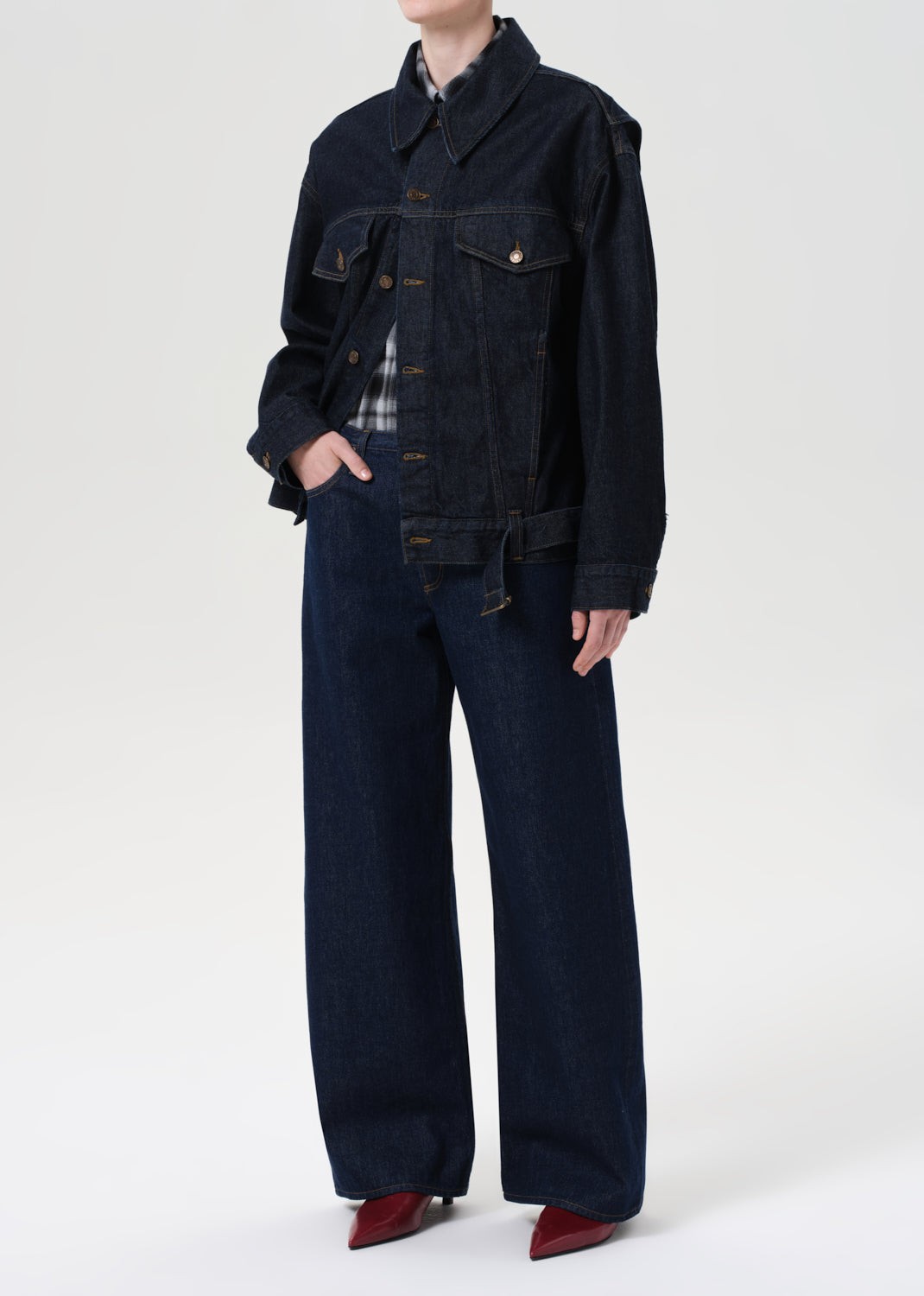 Person wearing a dark denim jacket and pants on a white background