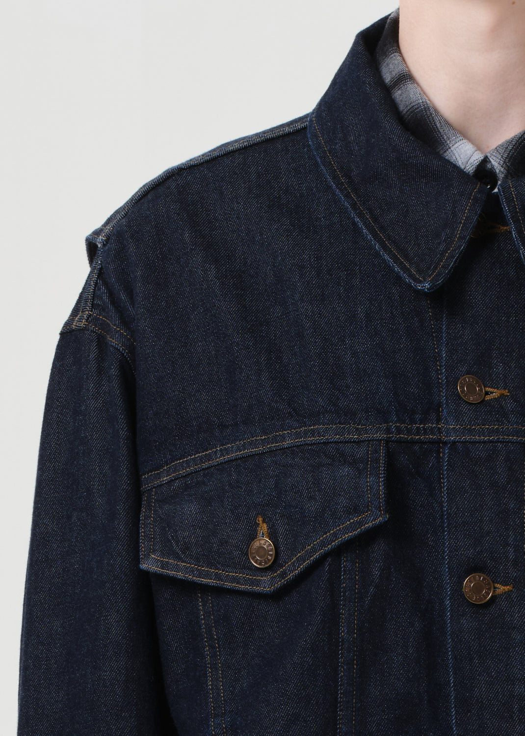 Dark denim jacket with button details on a plain background
