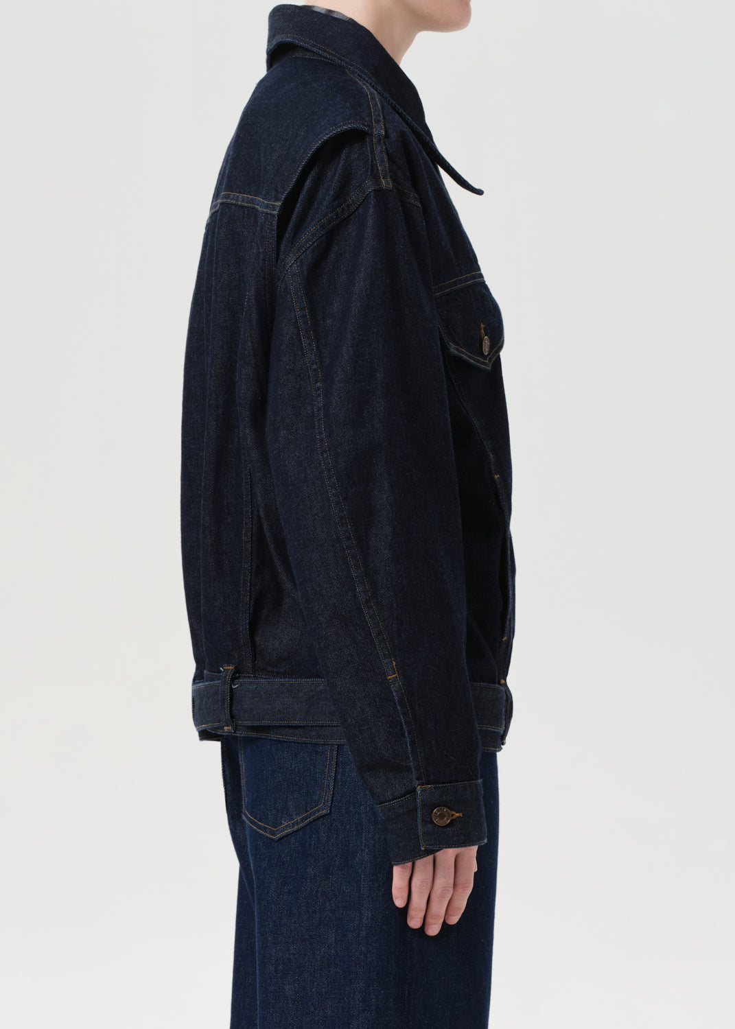 Dark denim jacket worn by a person on a light gray background