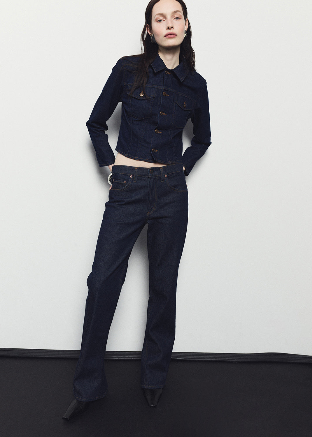 Person wearing a dark blue jacket and jeans against a white background