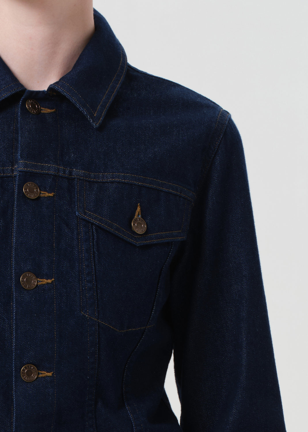 Dark denim jacket with gold buttons on a plain background