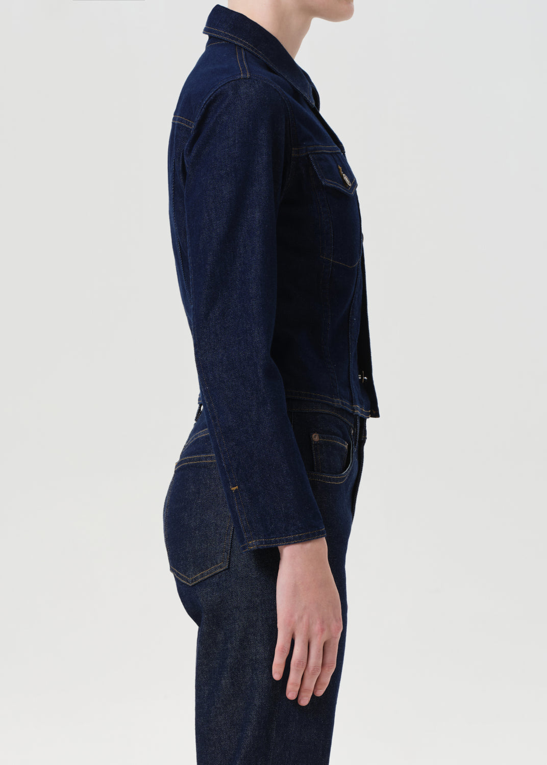 Person wearing a dark blue denim jacket on a light gray background