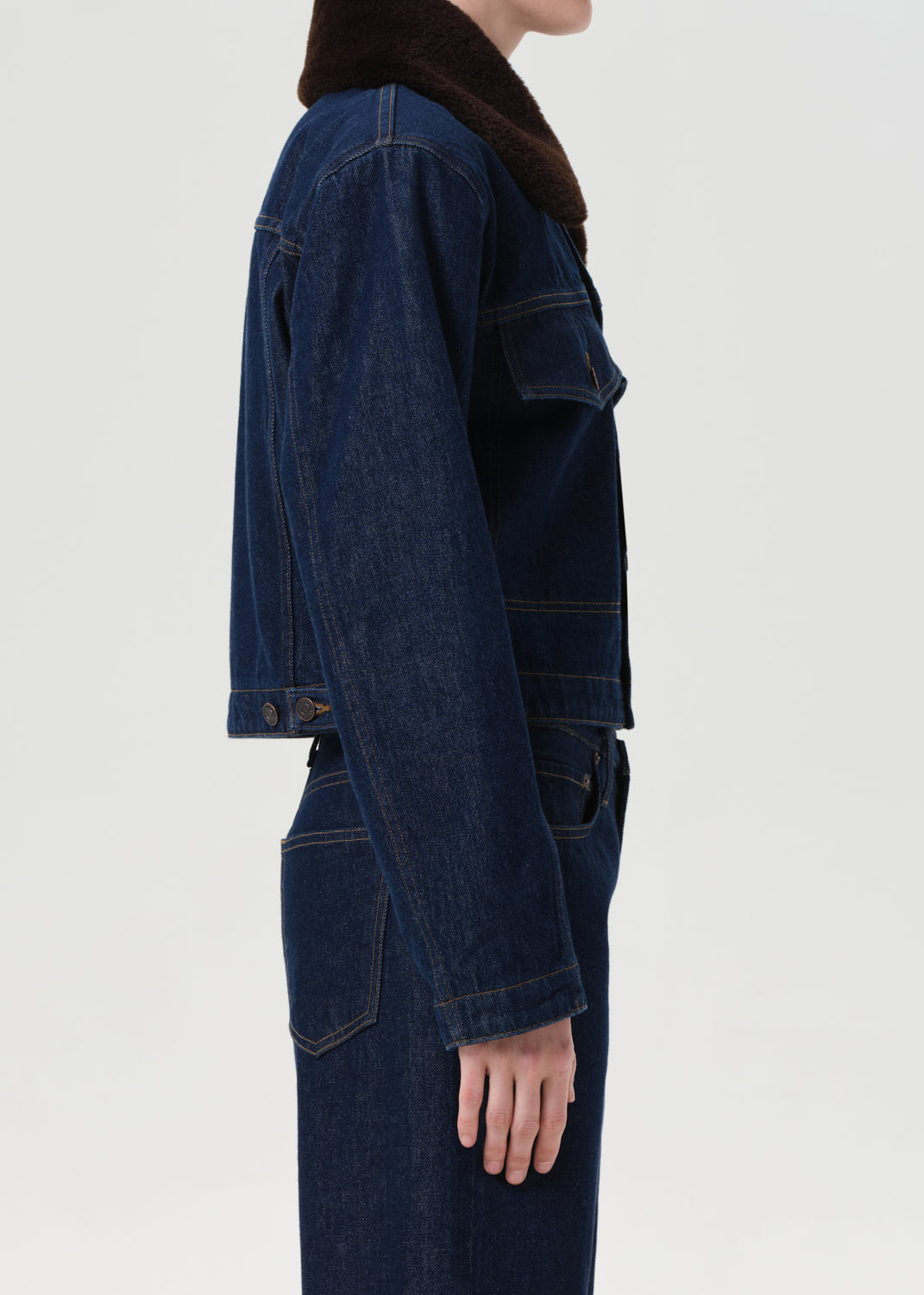 Person wearing a dark blue denim jacket on a white background
