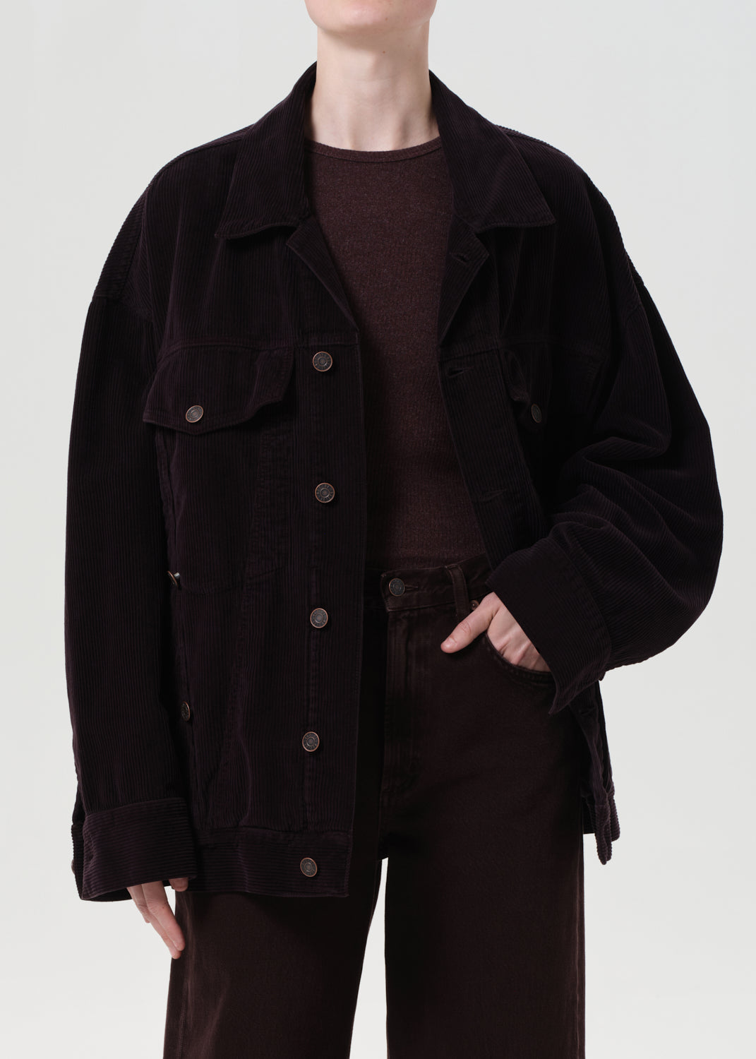 Person wearing a dark brown jacket and pants on a white background