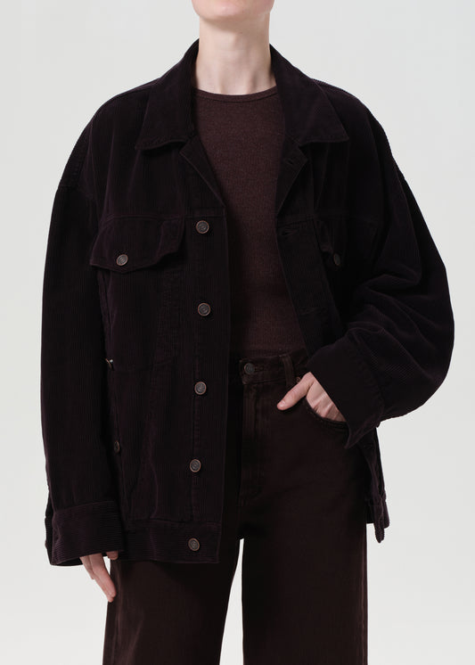Person wearing a dark brown jacket and pants on a white background