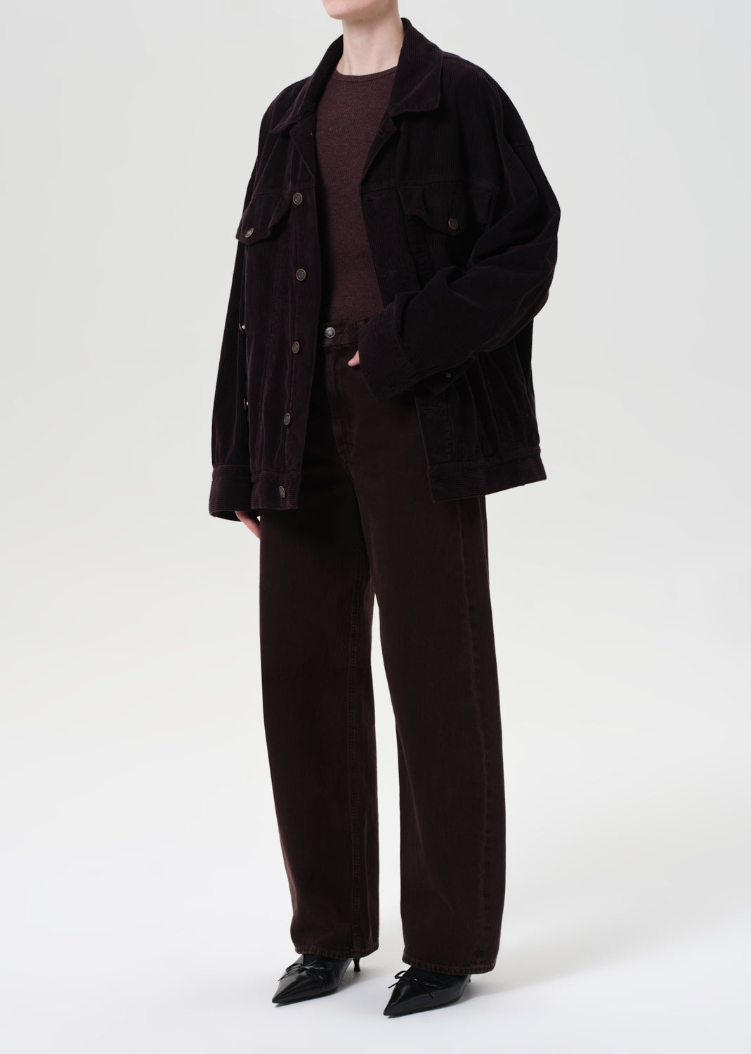 Person wearing a dark brown coat and pants on a white background