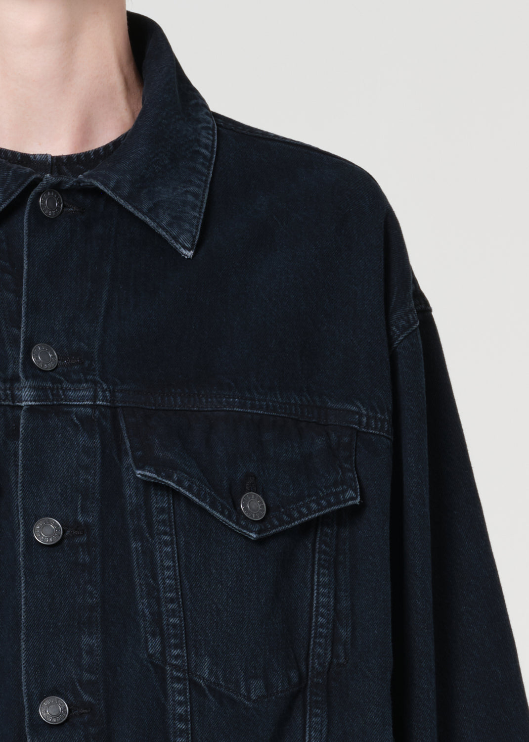 Dark denim jacket with button details on a plain background