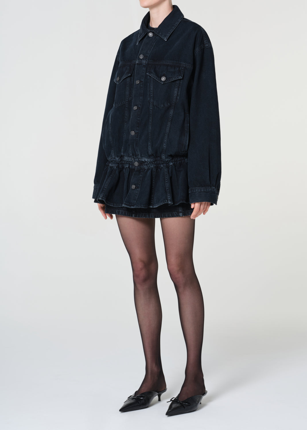 Person wearing a black denim dress with a white background