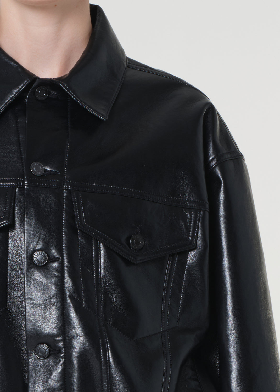 Close-up of a black leather jacket with a plain background