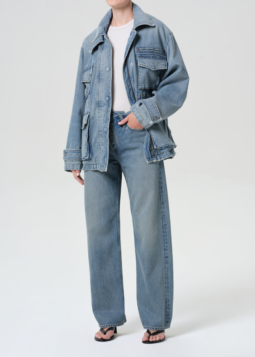 Person wearing a denim jacket and jeans on a white background
