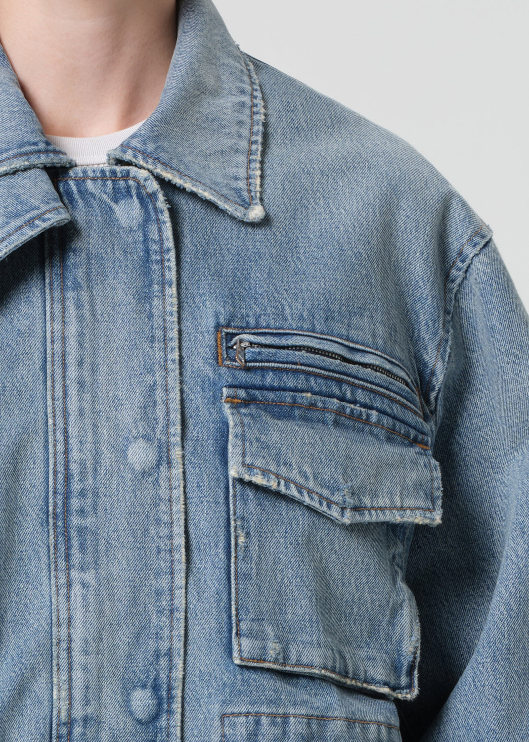 Close-up of a blue denim jacket with a pocket on a light gray background