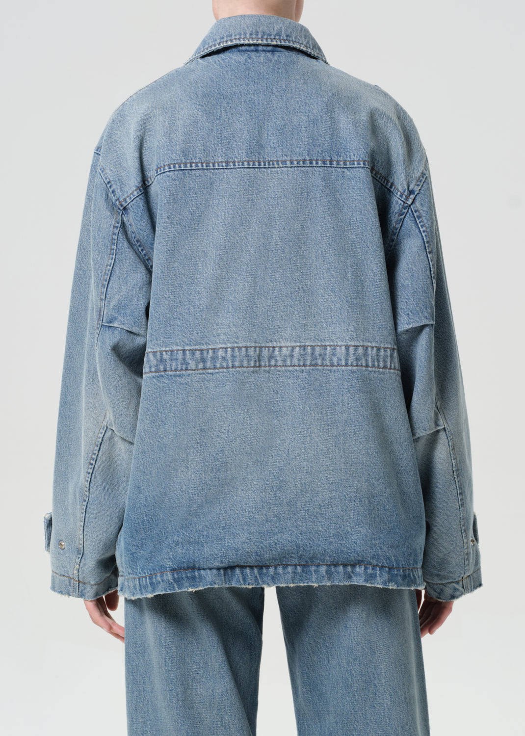 Blue denim jacket worn by a person on a plain background