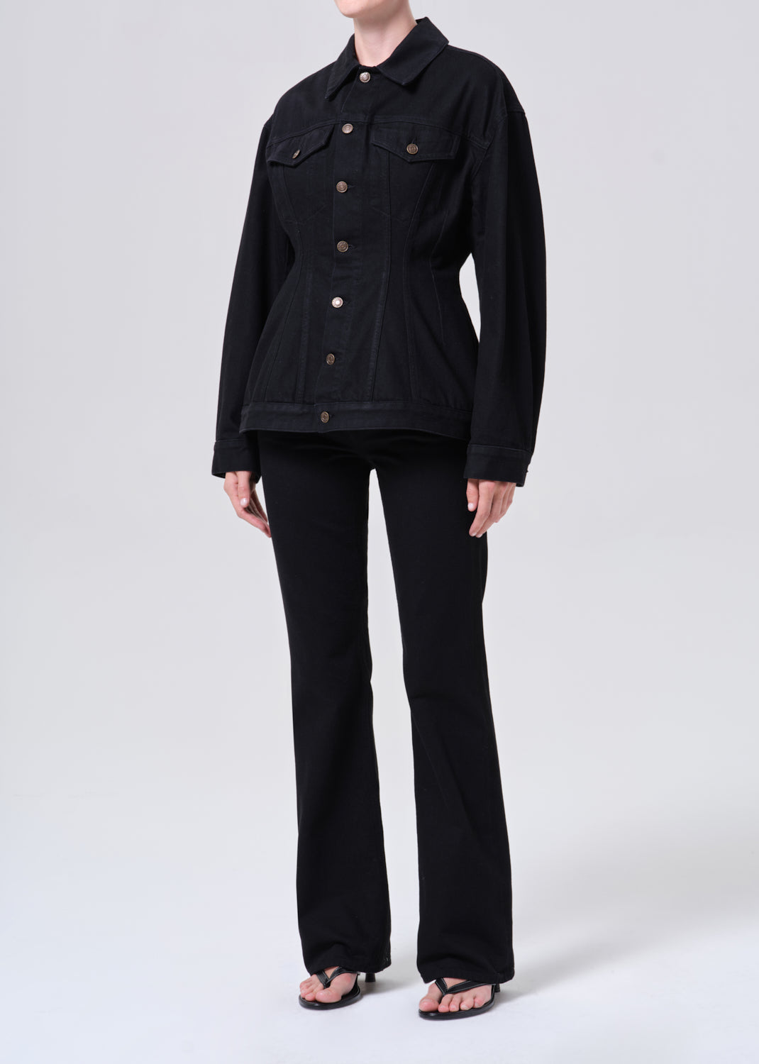 Person wearing a black denim jacket and pants on a white background