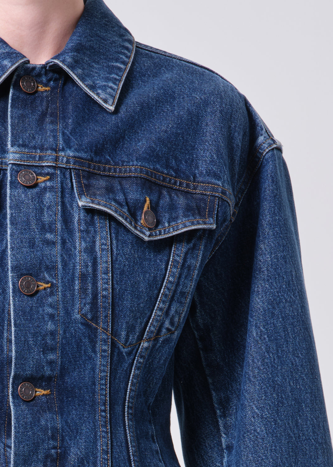 Close-up of a blue denim jacket with button details on a plain background