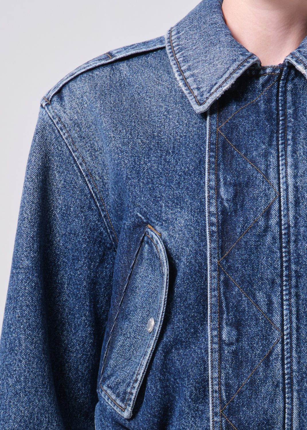 Close-up of a blue denim jacket with a plain background