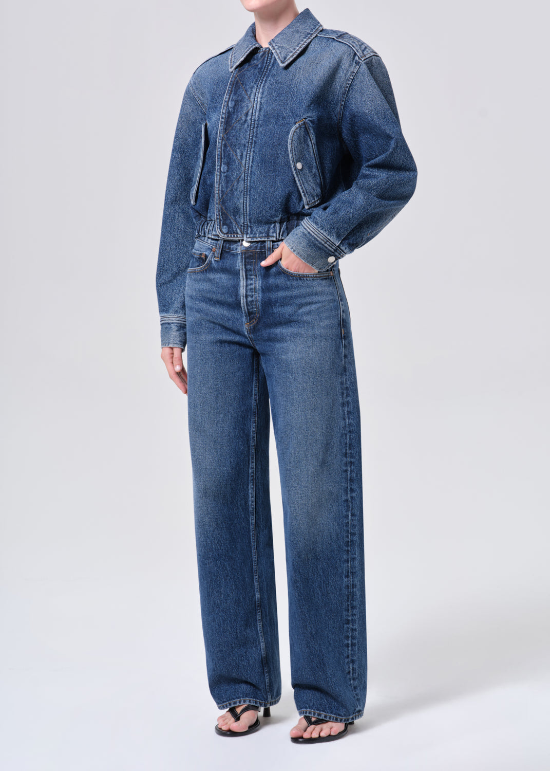 Person wearing a blue denim outfit on a white background