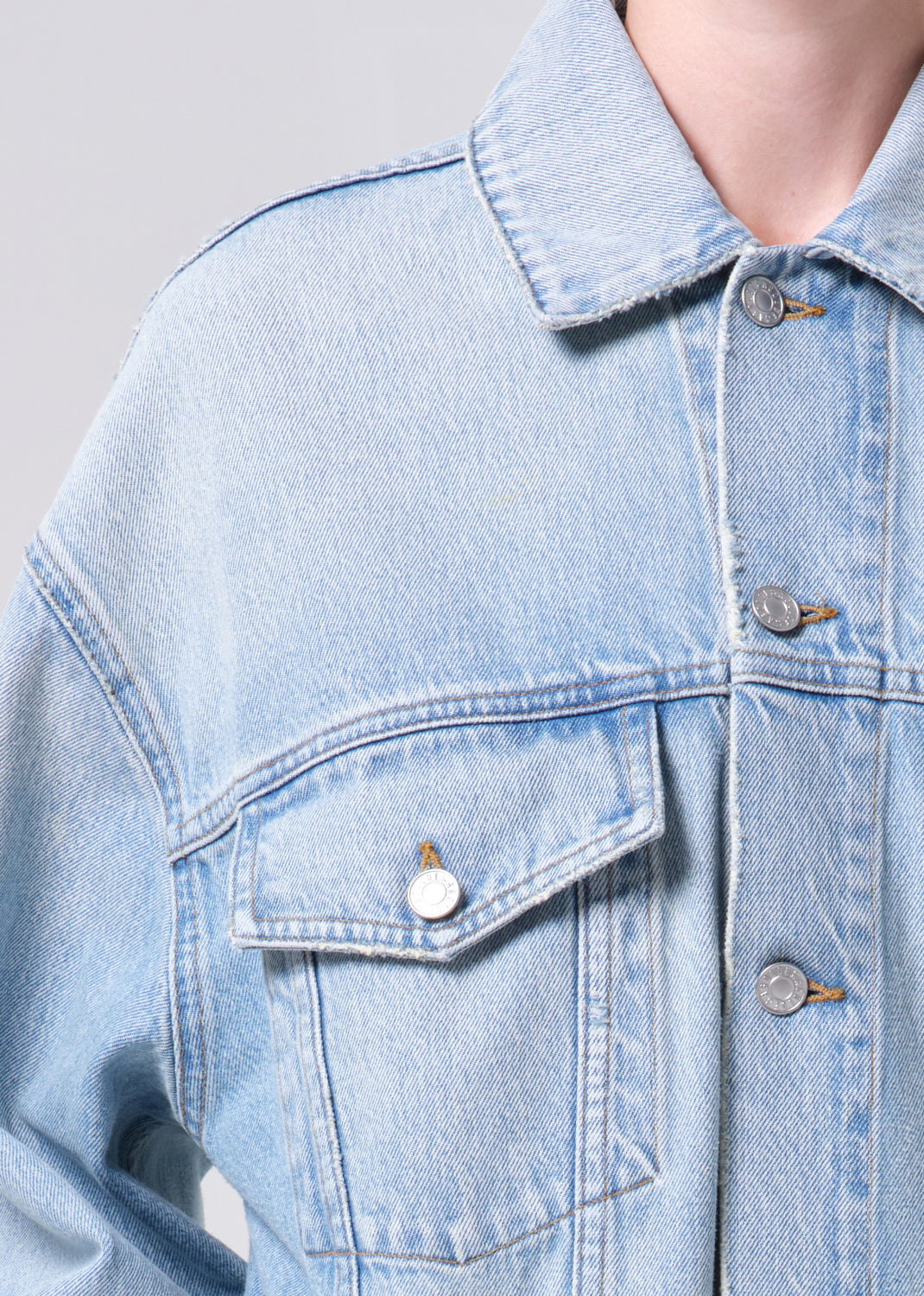 Light blue denim jacket with buttons on a neutral background