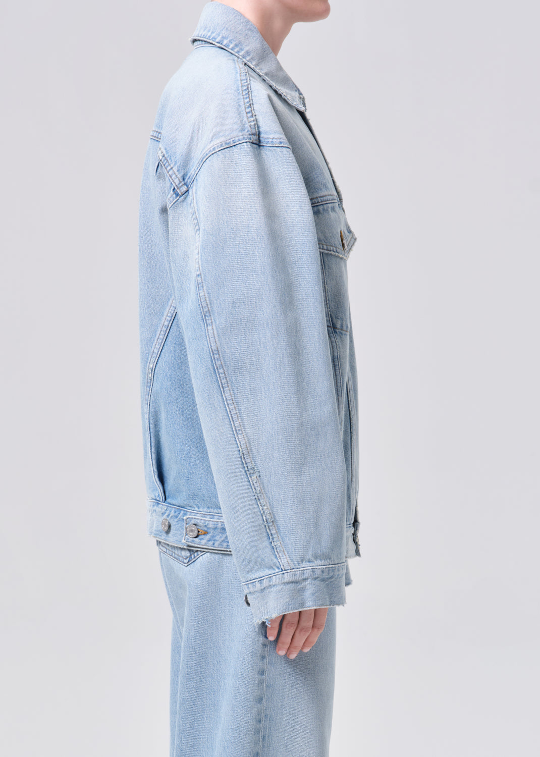 Light blue denim jacket worn by a person on a light gray background