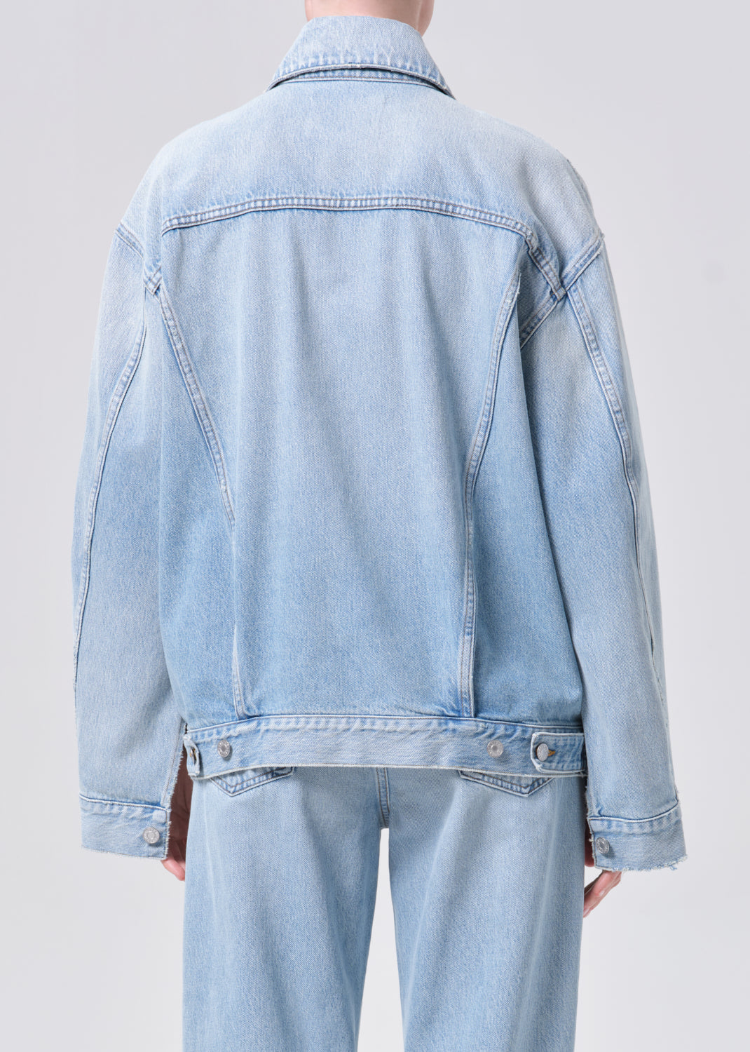 Light blue denim jacket and jeans on a plain background
