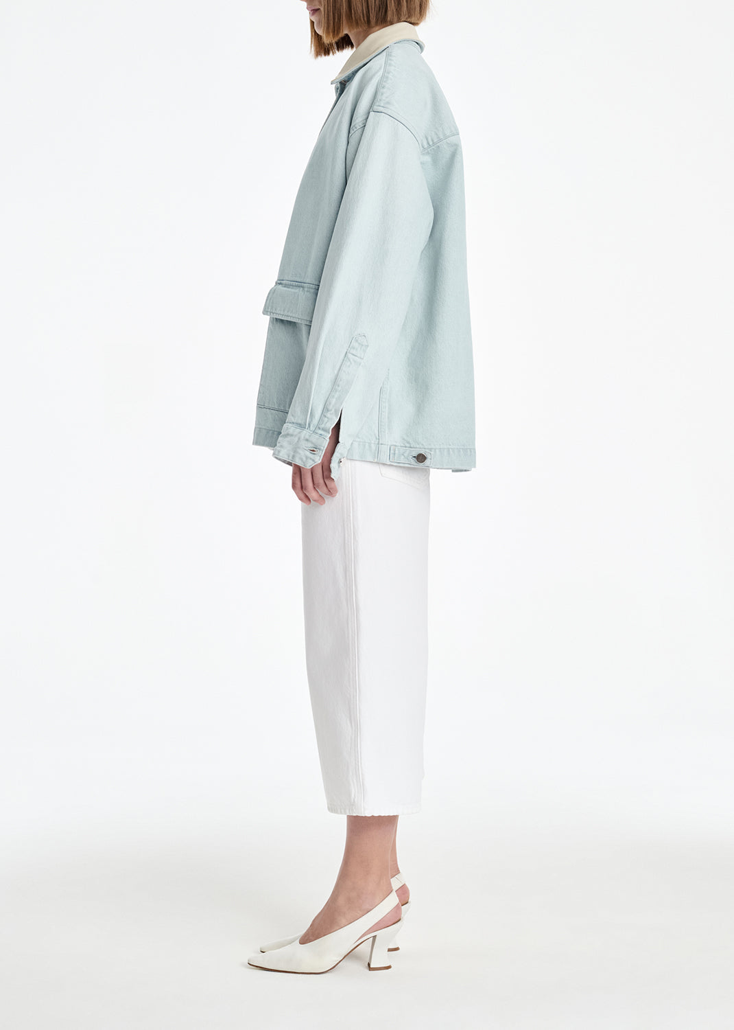 Person wearing a light blue jacket and white pants on a white background