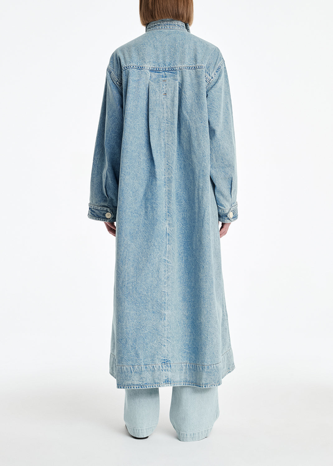 Person wearing a long denim dress on a white background