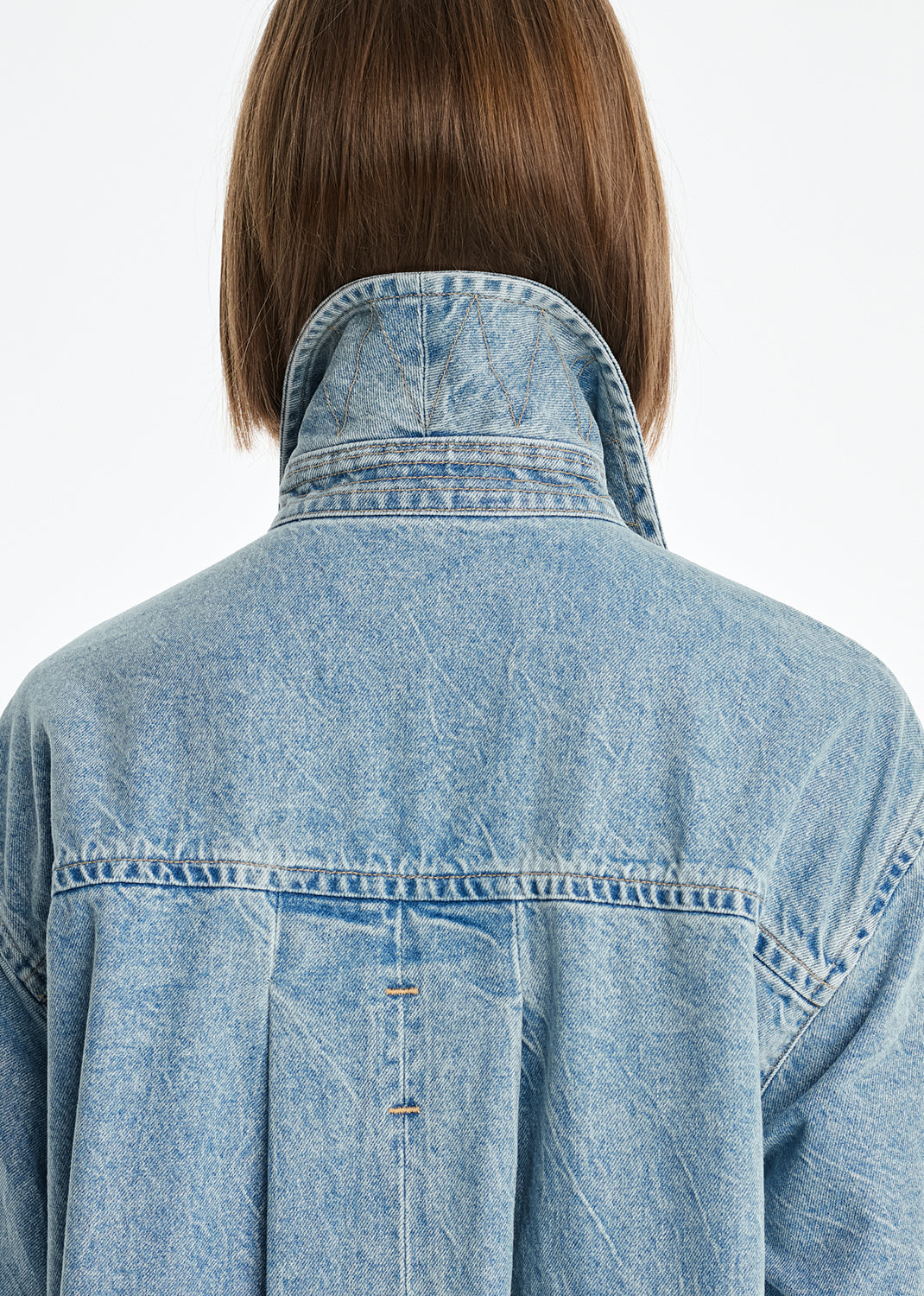 Person wearing a light blue denim jacket on a white background