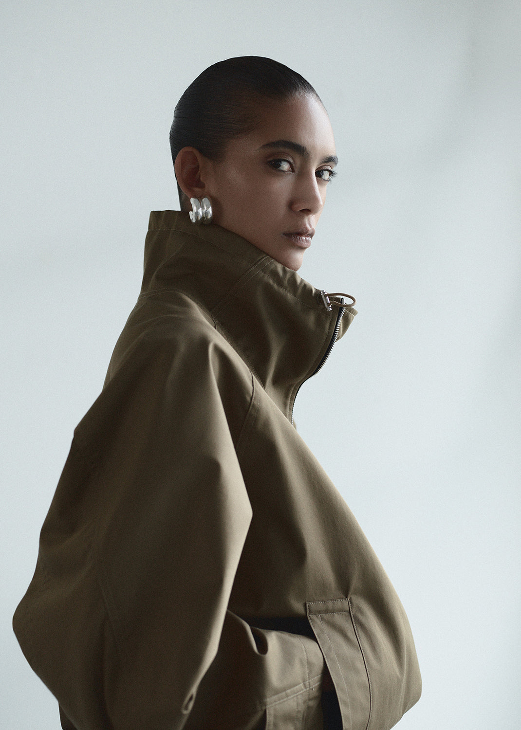 Person wearing a brown coat against a plain background