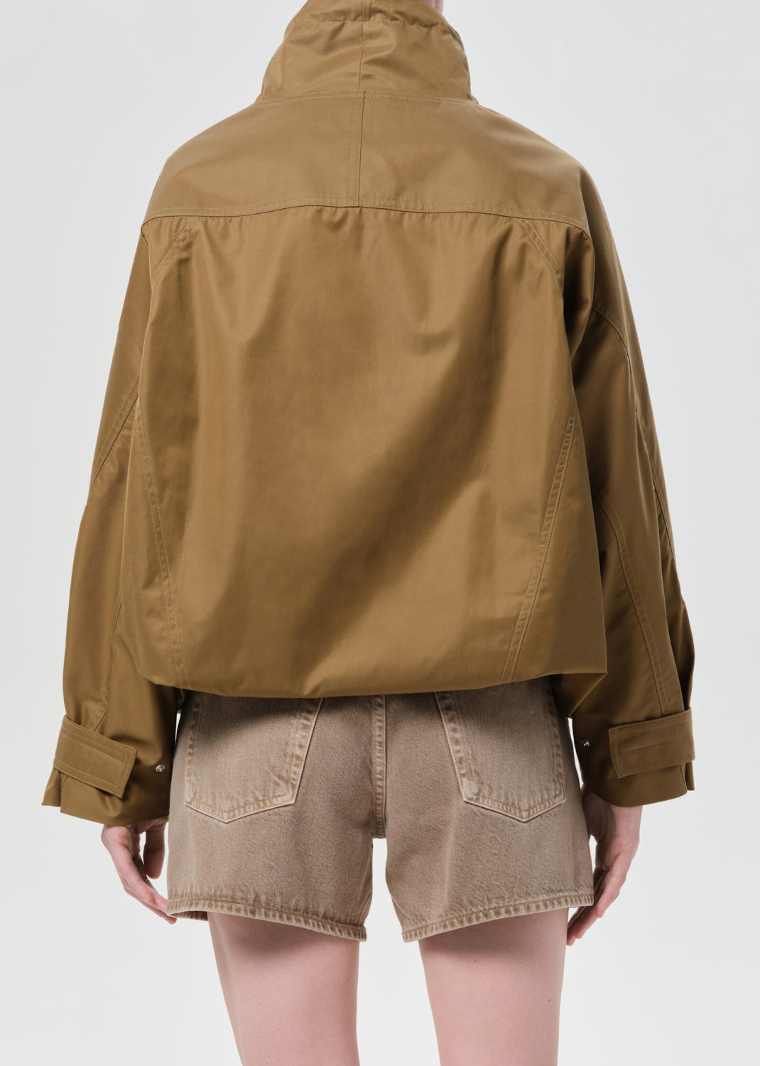 Person wearing a brown jacket and shorts on a white background