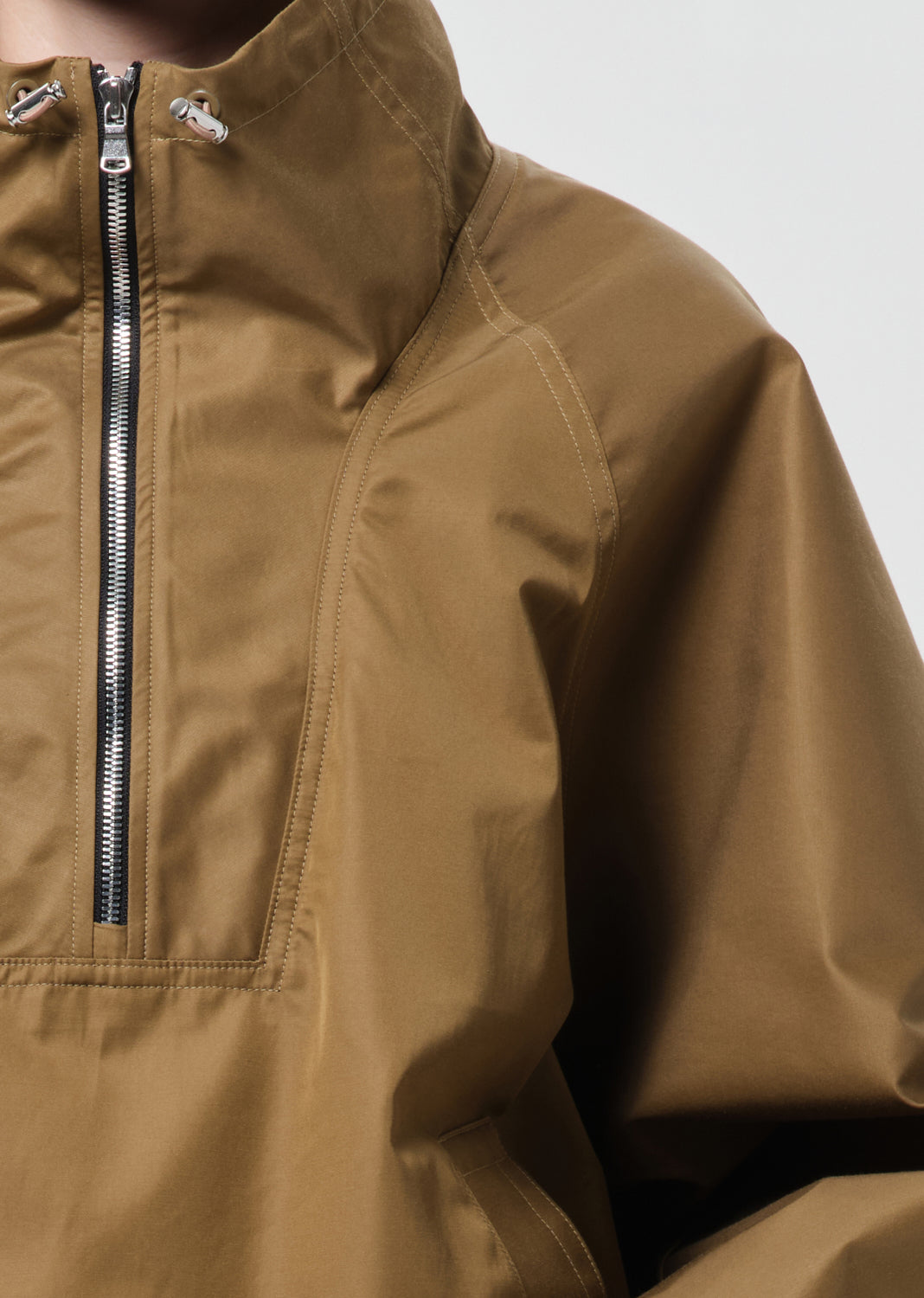 Close-up of a brown jacket with a zipper on a neutral background