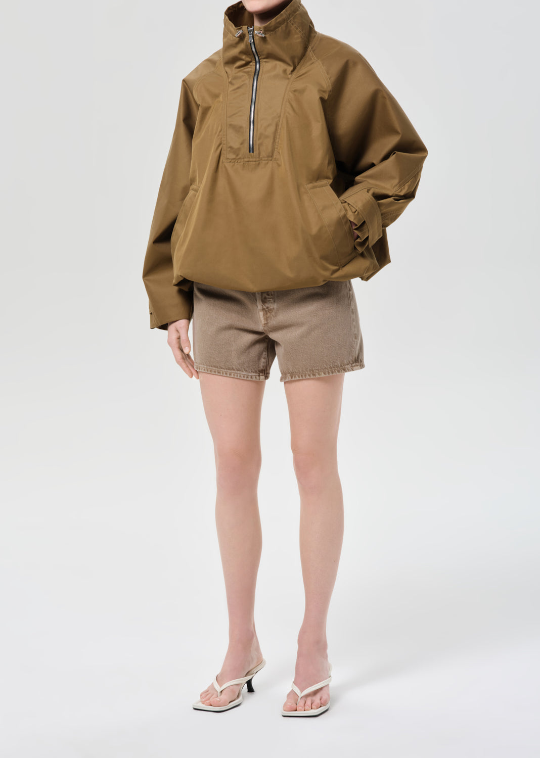 Person wearing a brown jacket and shorts on a white background