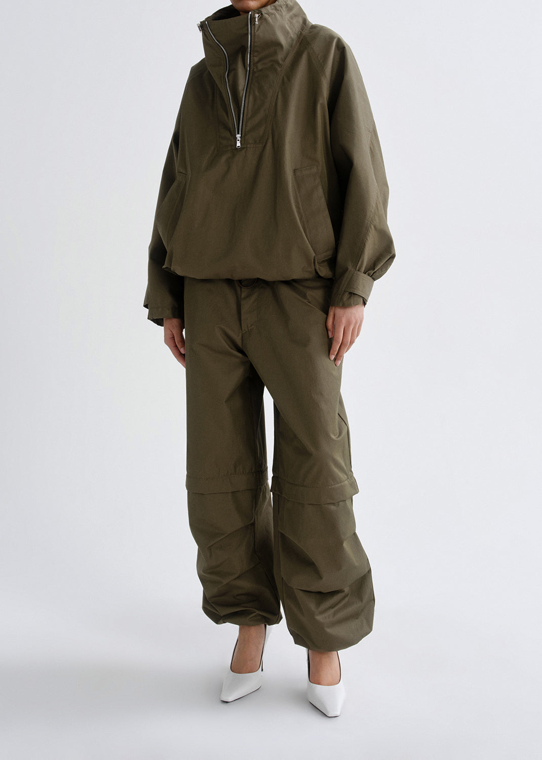 Person wearing an olive green outfit on a grey background