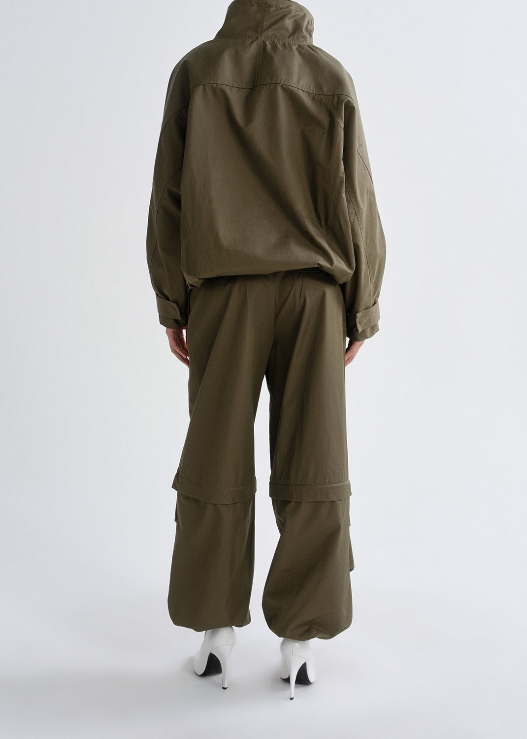 Person wearing a green tracksuit on a grey background