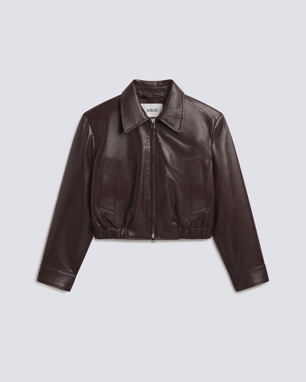 A dark brown faux leather cropped jacket with a collar, front zipper, and two front patch pockets, displayed on a light gray background.