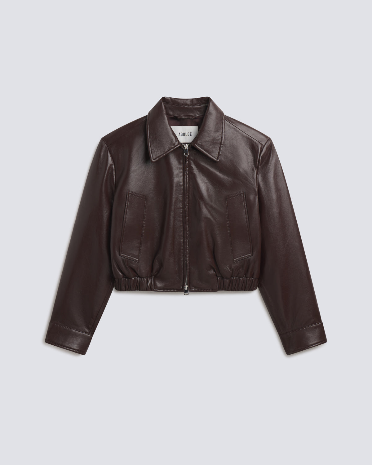 A dark brown faux leather cropped jacket with a collar, front zipper, and two front patch pockets, displayed on a light gray background.