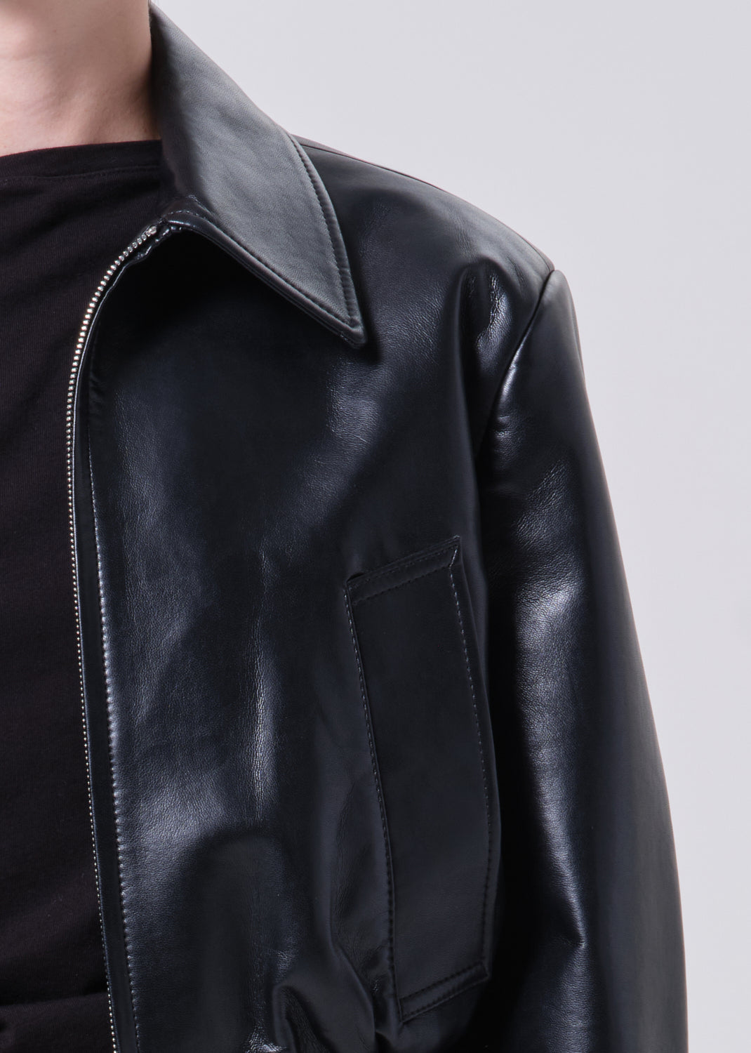 Black leather jacket with a gray collar on a light gray background