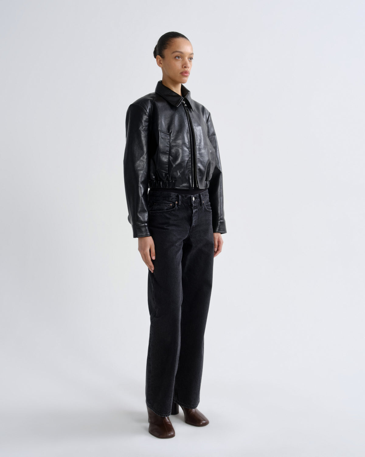 Person wearing a black leather jacket and pants on a white background