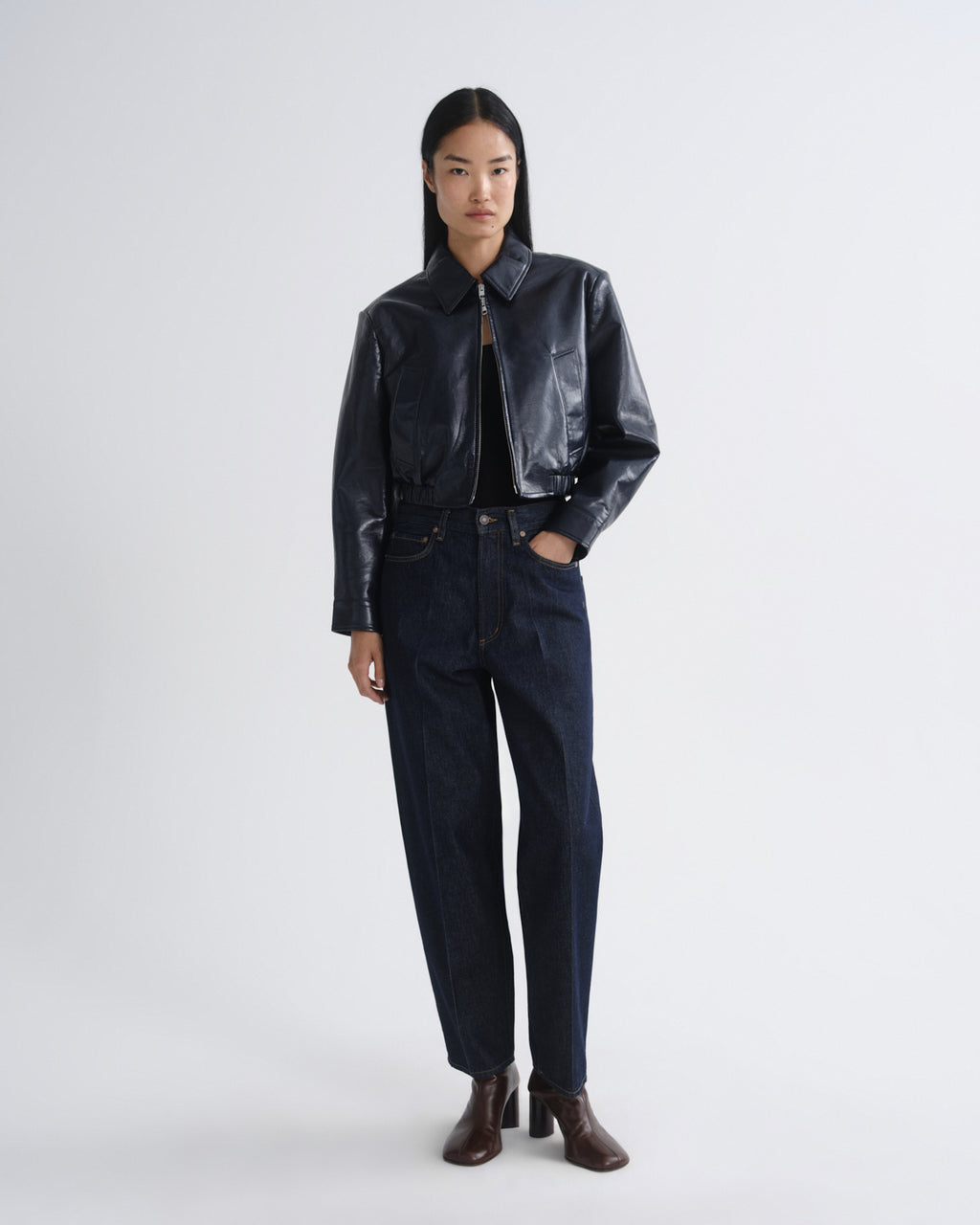 Person wearing a black leather jacket and pants on a white background