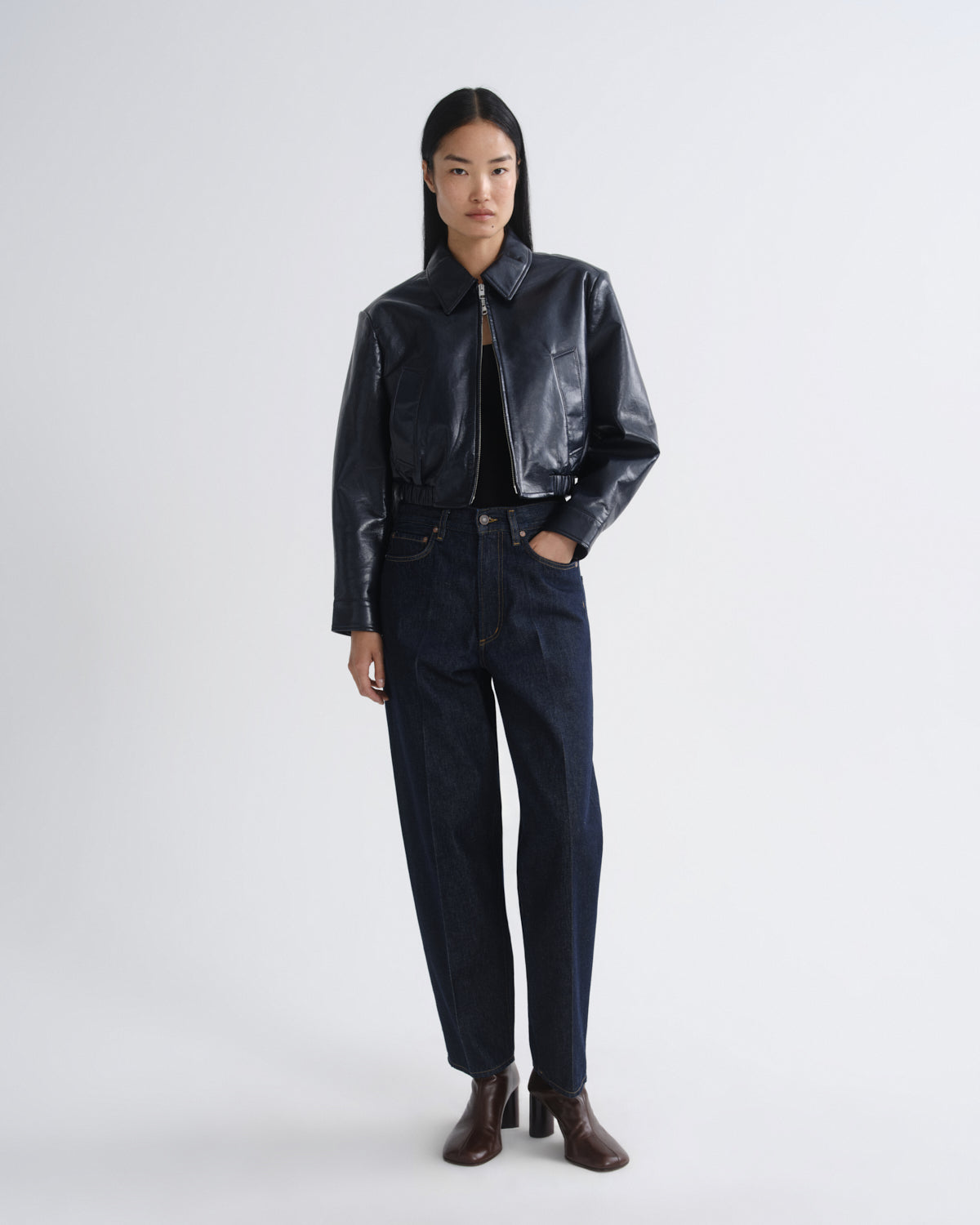 Person wearing a black leather jacket and pants on a white background