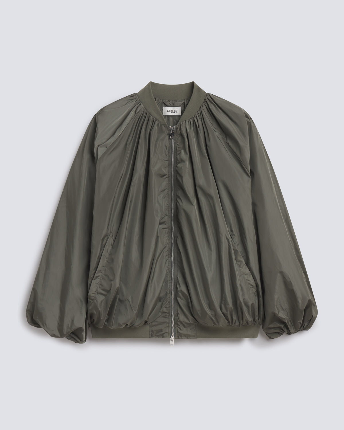 An olive green nylon bomber jacket with a gathered, pleated front design, ribbed collar, cuffs, and hem, shown flat on a light gray background.
